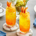 Two glasses of orange and yellow liquid with fruit slices, one with a close up of Fanale Mango Fruit Jam.