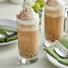 Two glasses of Fanale iced mocha with whipped cream and chocolate on a table with a spoon.