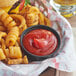 A cheeseburger and fries with Red Gold ketchup on a paper plate.