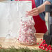 A person putting candy in an Acopa glass pine tree jar with a cork lid.