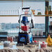 A Waring commercial blender in a kitchen with bowls of berries and fruit.