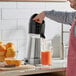 A man using an AvaMix citrus bar juicer to make orange juice.