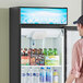 A man looking at a blue Avantco graphic sign panel on a refrigerator.