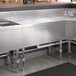 A Regency stainless steel underbar drainboard on a stainless steel counter in a kitchen.
