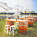 A Mod-Picket white fence set up in a grass field with wooden tables and white umbrellas.