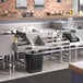 A Regency stainless steel cocktail station with a liquor display rack and cold plate on a counter.