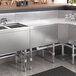A Regency stainless steel underbar drainboard on a counter in a professional kitchen.
