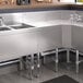 A Regency stainless steel underbar drainboard on a stainless steel counter above a stainless steel sink.