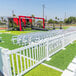 A Mod-Traditional white fence panel in a grass field with white chairs on it.