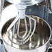 A Vollrath flat beater in a mixer with a bowl in it.