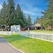 A white Mod-Picket fence panel on a lawn with people walking.