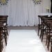 A white FloorEXP carpet runner with chairs set up for a wedding ceremony.