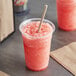 A cup of pink Original Slushie Company Watermelon Carbonated Slushy with a straw.
