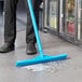 A person cleaning the floor with a Vikan blue rubber floor squeegee.