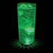 A customizable plastic cup with green LED lights filled with a green drink on a bar counter.