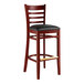 A Lancaster Table & Seating mahogany wood bar stool with black vinyl seat.