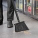 A person sweeping the floor with a black angled Vikan broom head.