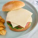 A cheese burger with Daiya Vegan Swiss Cheese and chips on a plate.