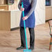 A man in an apron using a blue Vikan Ultra-Hygienic handle.