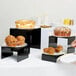 A plate of muffins on a black acrylic riser.