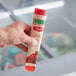 A hand holding a Luigi's Cherry Italian Ice tube.