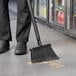 A person sweeping the floor with a Vikan black angled broom.