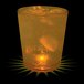 A customizable plastic rocks cup with ice and orange liquid, with a yellow LED light in it.