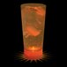 A 10 oz. customizable plastic cup with orange LED light filled with orange liquid and ice cubes.