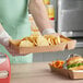 A person holding a Carnival King paper food tray with a burger and chips.