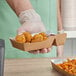 A hand holding a Carnival King small two-compartment paper food tray with fried chicken nuggets and fried chicken.