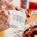 A person using a Choice lemon-scented moist towelette to clean their hands over a plate of food in a pizza parlor.