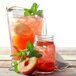 A glass of peach iced tea with a peach next to it.