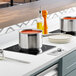 A Cooking Performance Group drop-in induction range on a counter in a professional kitchen with pots on it.