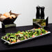 An American Metalcraft trapezoid melamine serving platter holding salad and bread on a table.