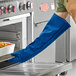 A person wearing a Tucker Safety blue Nomex oven mitt.