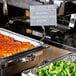 American Metalcraft double-sided sign clip holding a sign in a tray of food.