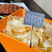 An American Metalcraft double-sided flexible sign clip holding a sign in a bowl of chips on a table.