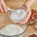 A person pouring white powder into a bowl.