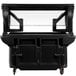 A black food cart with a clear glass top and standard casters.