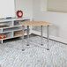 A Flash Furniture natural hexagonal desk with adjustable legs in a room with a table and chairs.