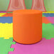 A Flash Furniture orange flexible seating circle ottoman on a colorful floor.