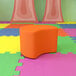 A Flash Furniture Nicholas orange soft seating moon ottoman on a colorful surface.