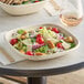 A salad in a World Centric compostable square fiber bowl with a wooden fork.