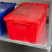 Two red and blue plastic Vollrath Tote 'N Store containers on a metal shelf.