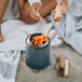 A person using a blue Solo Stove Mesa tabletop fire pit on a patio table near the beach.