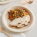 A World Centric compostable fiber plate with meat and vegetables on a table.