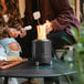 A couple sitting at a table with a Solo Stove Mesa tabletop fire pit with a fire in it.