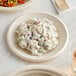 A World Centric compostable plate with potato salad, on a table.