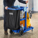 A man pushing a Lavex blue janitor cart with cleaning supplies.