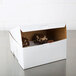 A white customizable bakery box with cupcakes inside on a bakery counter.